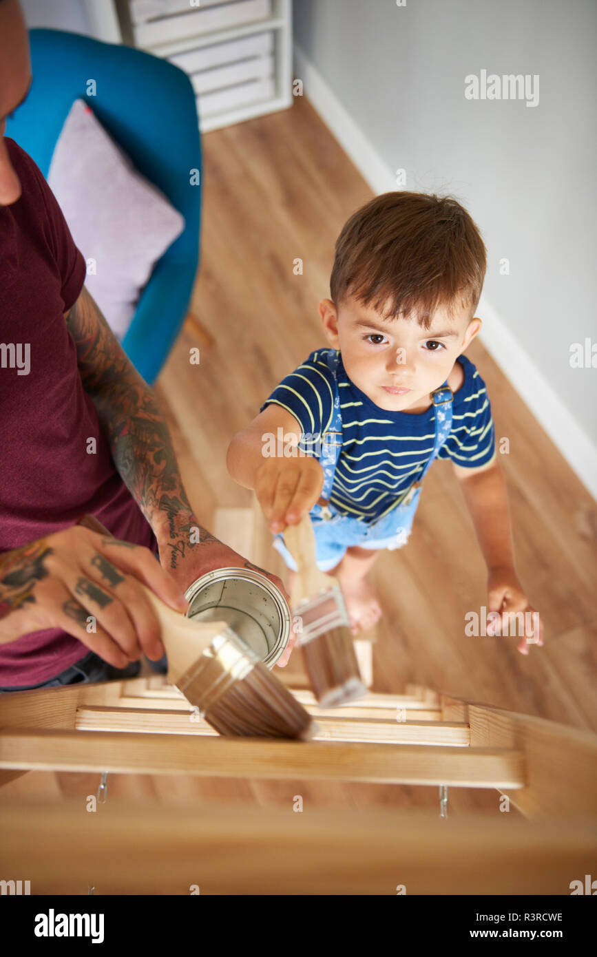 Padre e hijo de pintar una escalera juntos en casa Foto de stock
