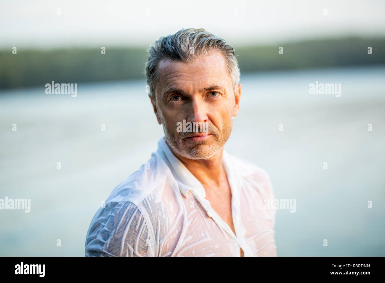 Retrato de hombre maduro, vistiendo camisa blanca húmeda en el lago Foto de stock