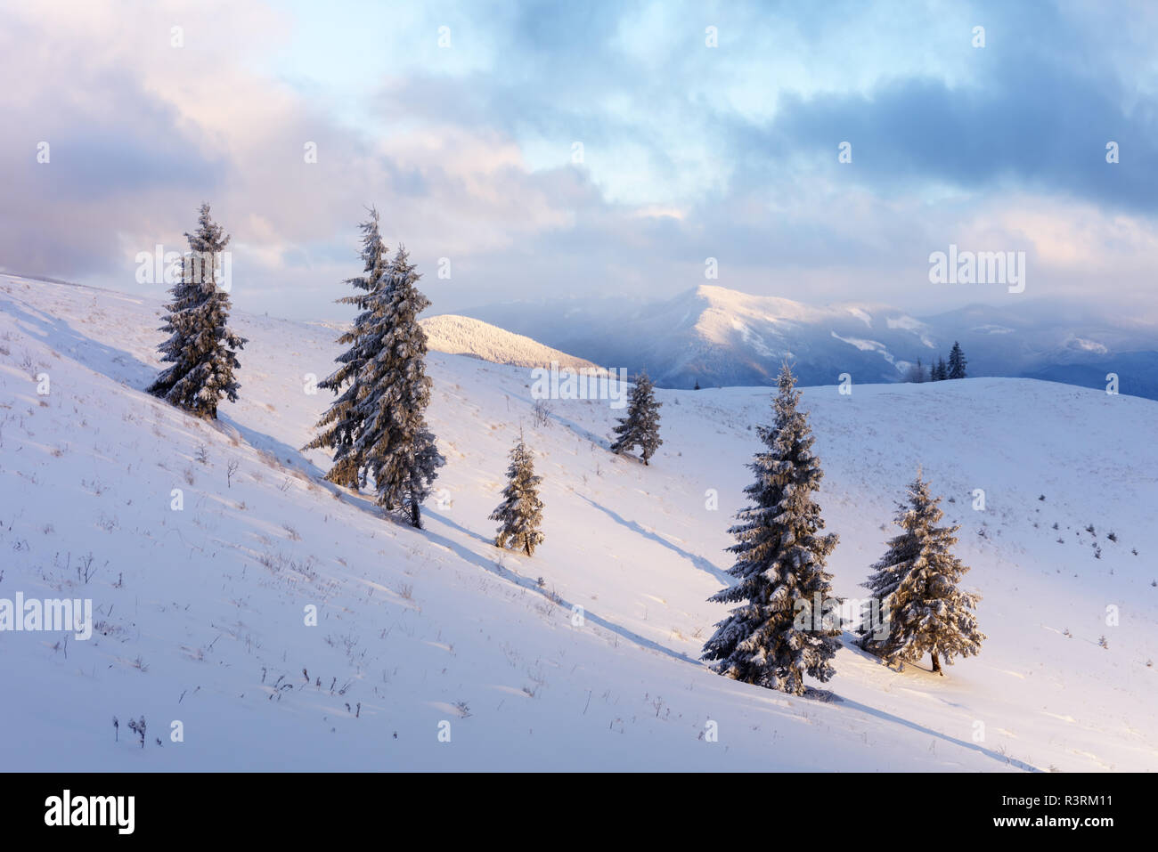 Fantastic orange paisaje invernal en montañas nevadas iluminado por la luz solar. Dramática escena invernal con árboles nevados. Concepto de vacaciones de Navidad. Foto de stock