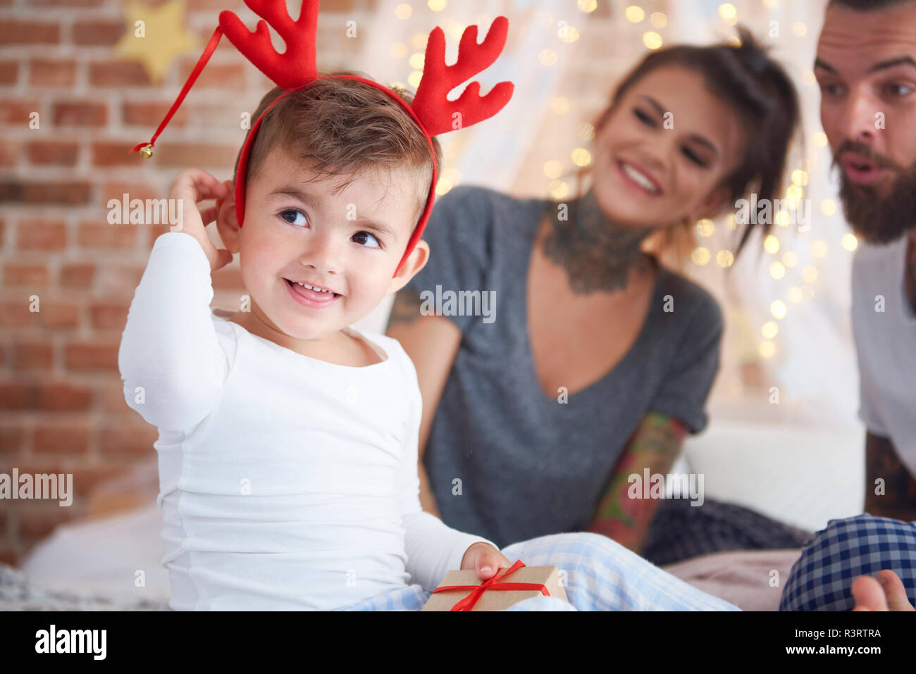 Chico lindo en traje de reno en el tiempo de Navidad en la cama Foto de stock