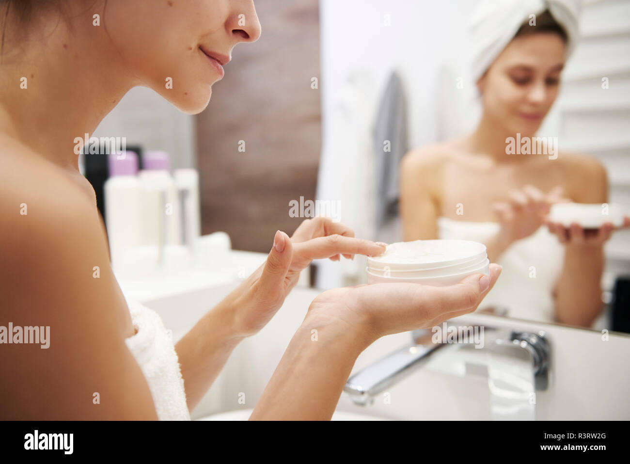 Mujer joven de aplicar la crema hidratante en el baño, vista parcial Foto de stock