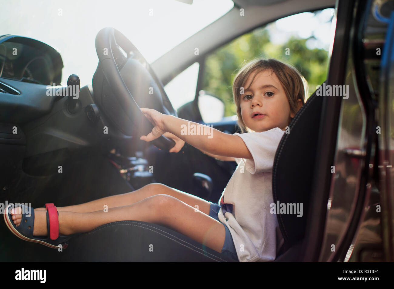 Retrato de niño sentado en el asiento del conductor de un coche Foto de stock