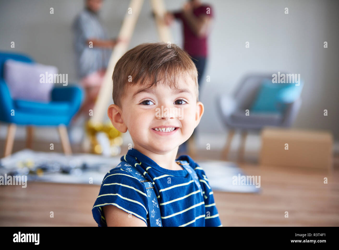 Retrato de niño sonriente con sus padres en casa en segundo plano. Foto de stock