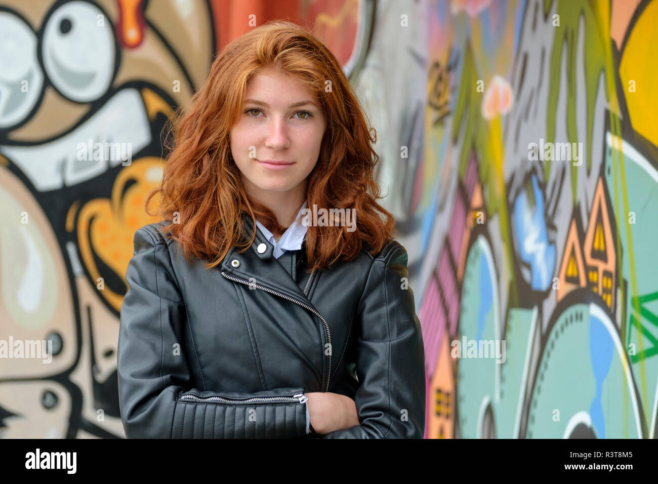 Italia, Finale Ligure, retrato de una adolescente pelirroja vistiendo la chaqueta de cuero negro en la parte delantera de mural Foto de stock