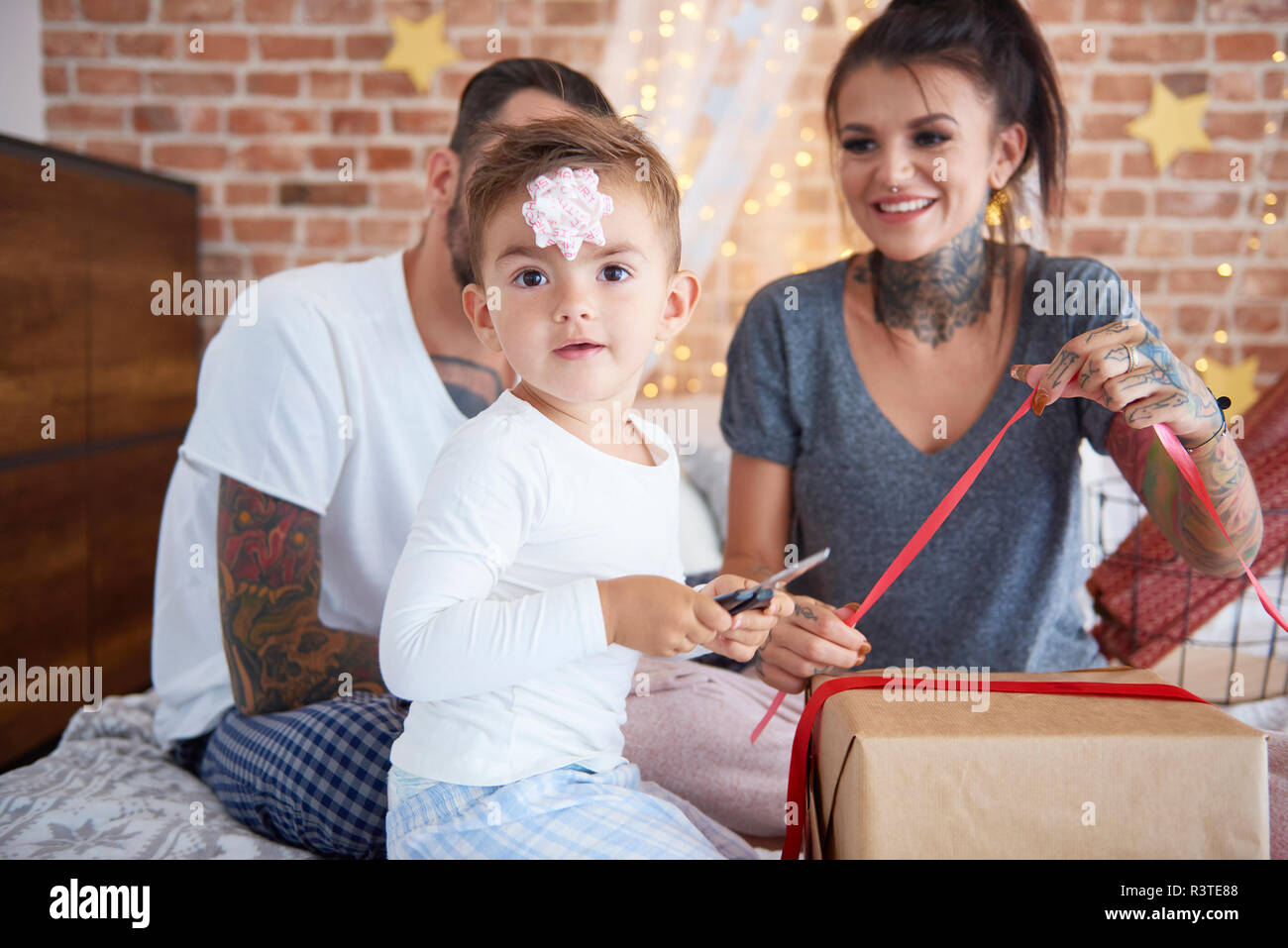 Retrato de niño abriendo regalo de Navidad con sus padres en la cama Foto de stock