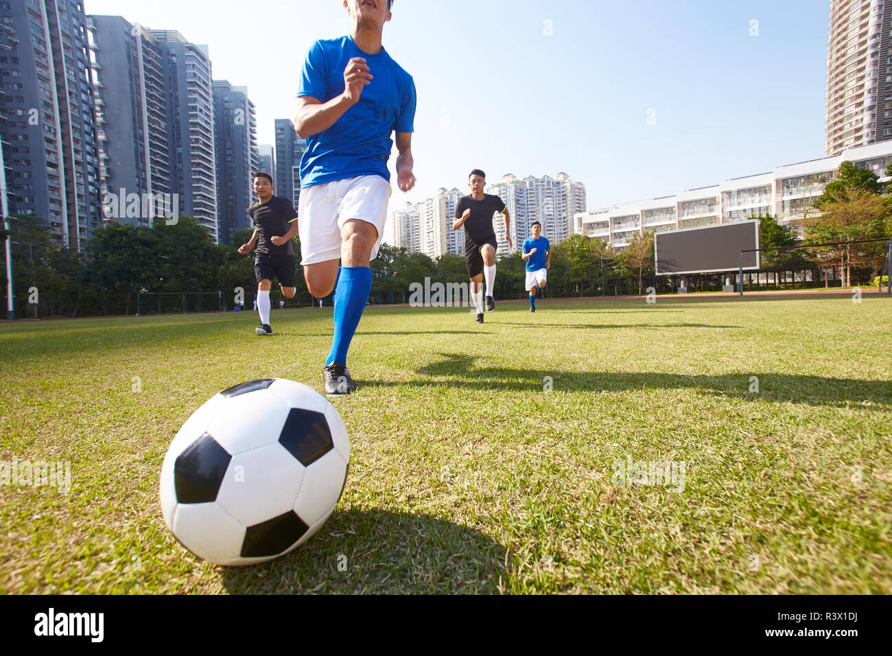 Los jóvenes jugadores de fútbol asiático persiguiendo el balón durante un partido Foto de stock