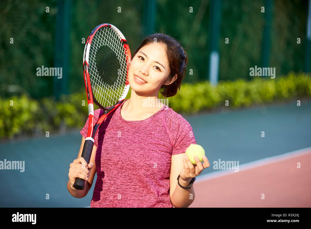 Outdoor retrato de un joven jugador de tenis Asia mirando a la cámara sonriendo Foto de stock