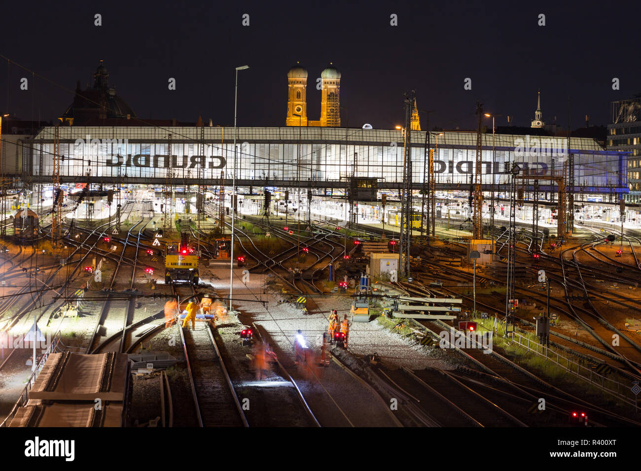 Estación central con pistas iluminadas en la noche, detrás de la Iglesia de Nuestra Señora, Munich, Alemania Foto de stock