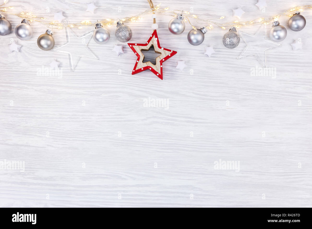 Las vacaciones de año nuevo fondo. Junta de madera blanca con guirnaldas de luz decorado con bolas de navidad y laicos plana de estrellas. Foto de stock