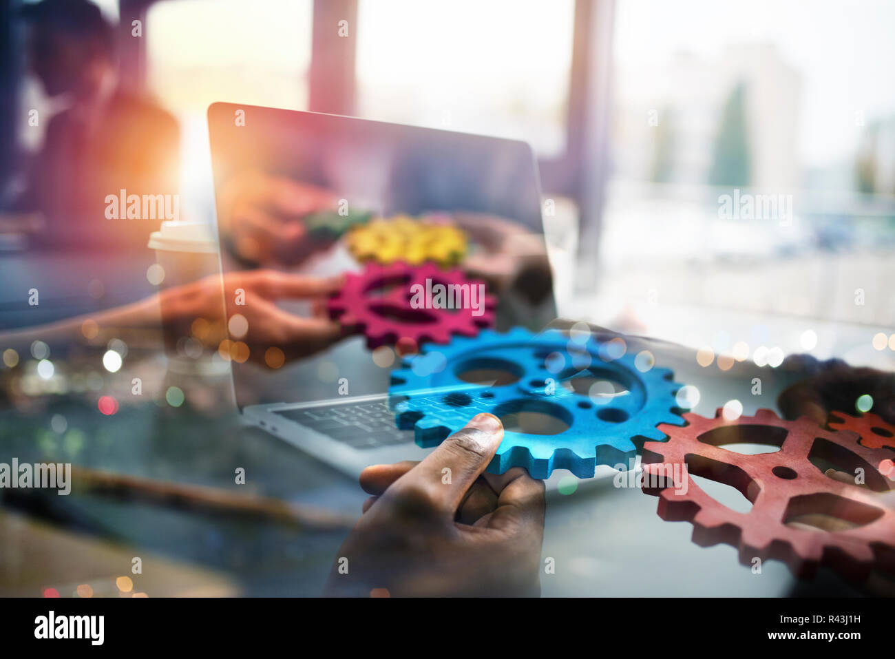 La gente de negocios con engranajes en mano que salir desde un portátil. concepto de cooperación y trabajo en equipo a distancia. Exposición doble Foto de stock
