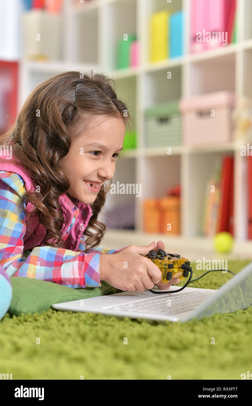 Linda niña jugando con juegos de ordenador portátil Foto de stock
