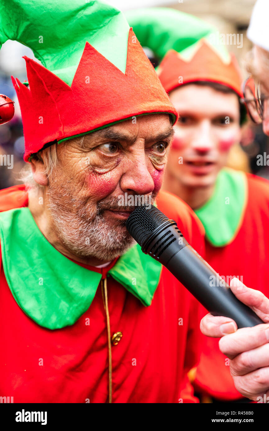 Uno de Santa's Helper, un hombre maduro, vestido y compuesto como un elfo, teniendo en micrófono celebrada por el entrevistador invisible durante el giro de las luces de Navidad en Ramsgate. Foto de stock