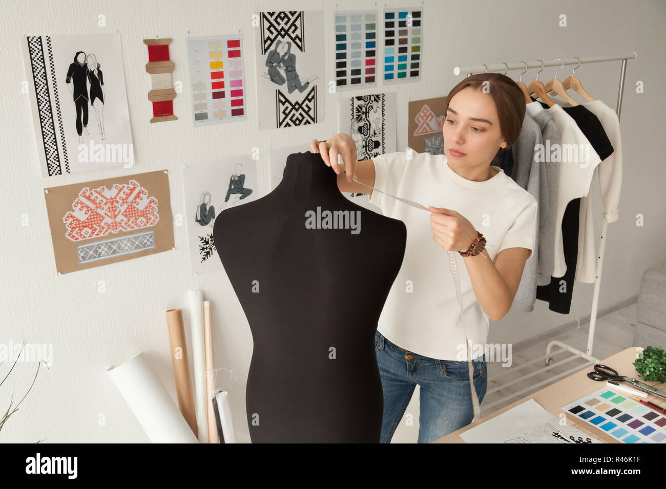 Diseñador de ropa femenina tomando mediciones, maniquí ficticia Foto de stock