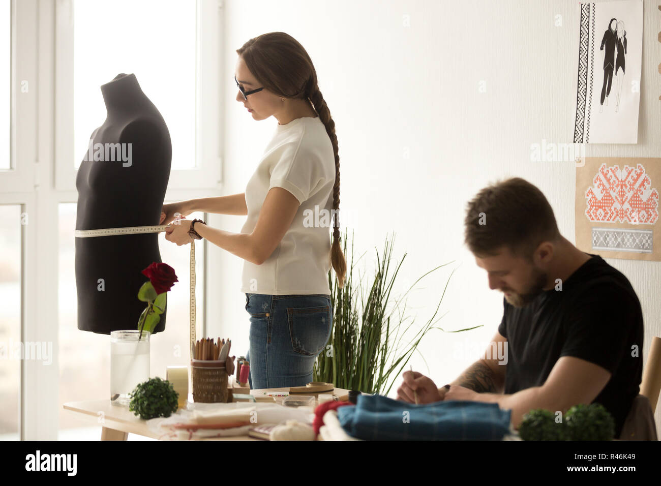 Diseñador de ropa femenina tomando medidas mientras que assistan ficticia Foto de stock