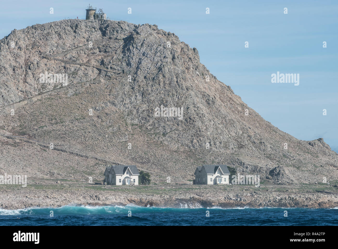 El único edificio en las Islas Farallón son estas pequeñas casas blancas donde duermen los científicos visitantes y el faro ontop de la colina. Foto de stock