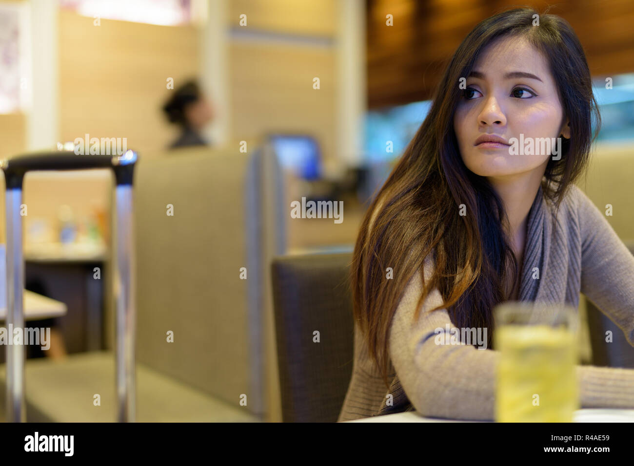 Asiática hermosa joven mujer sentada en el interior del restaurante Foto de stock