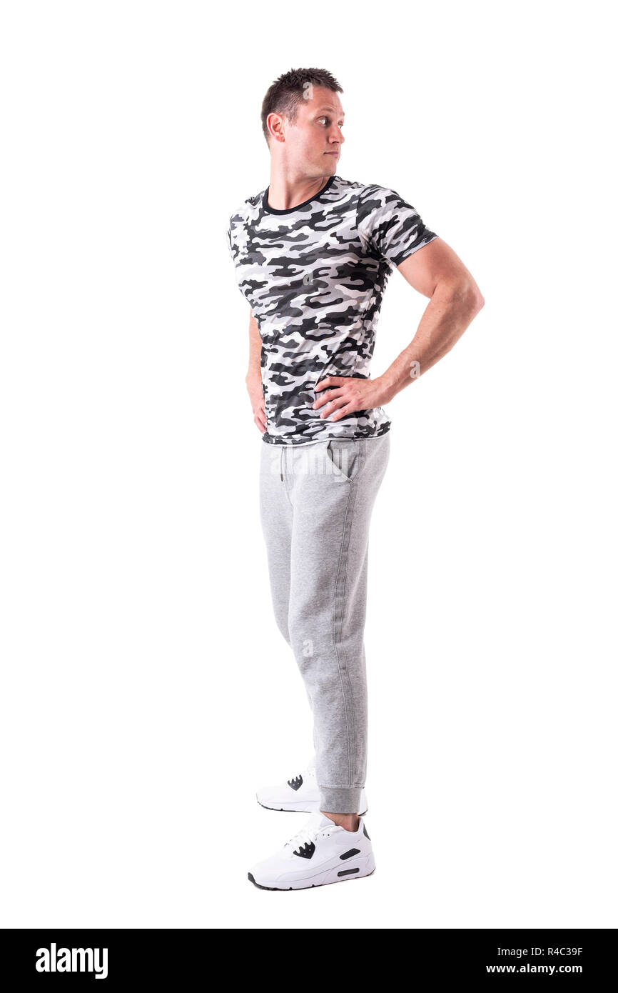 Apuesto hombre atlética en pantalones de sudadera y camiseta de camuflaje  mirando por encima del hombro. Cuerpo completo aislado sobre fondo blanco  Fotografía de stock - Alamy