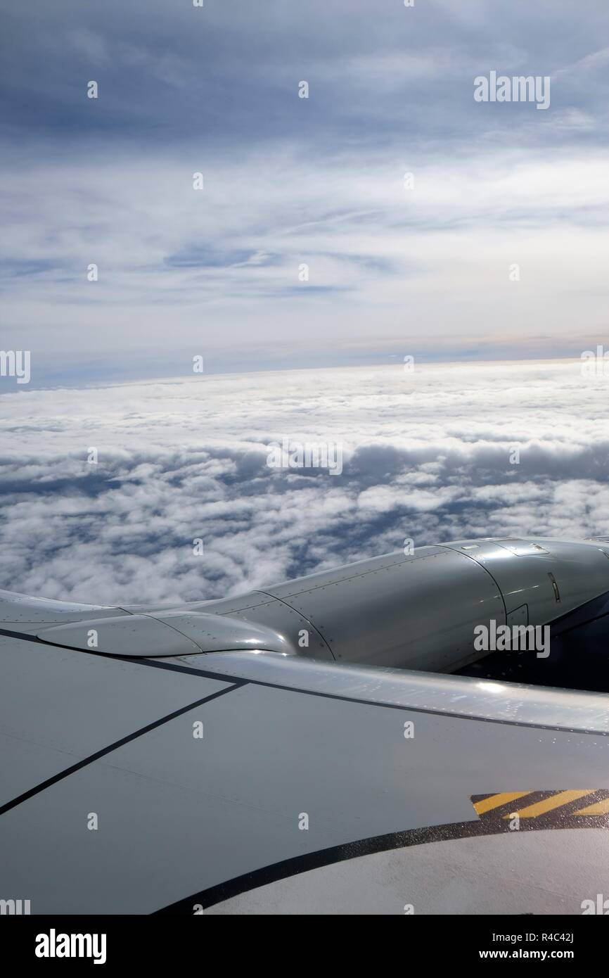Vista de las nubes y el cielo desde un avión; ventana vista parcial del ala y motor de turbina. Foto de stock