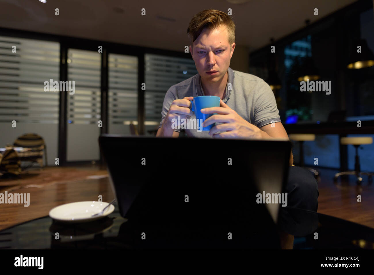 Joven apuesto hombre utilizando el portátil en el salón Foto de stock