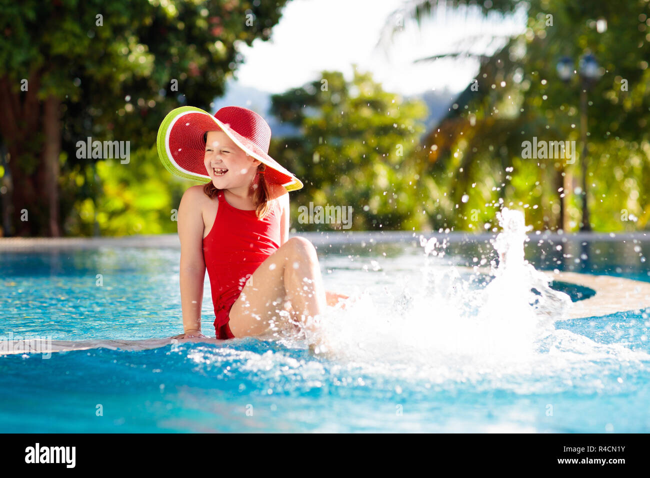 Niños en la piscina. Vacaciones tropicales para familia con niños. Niña  vestidos de rojo sandía bañador y sombrero para el sol jugando en la  piscina de exo Fotografía de stock - Alamy