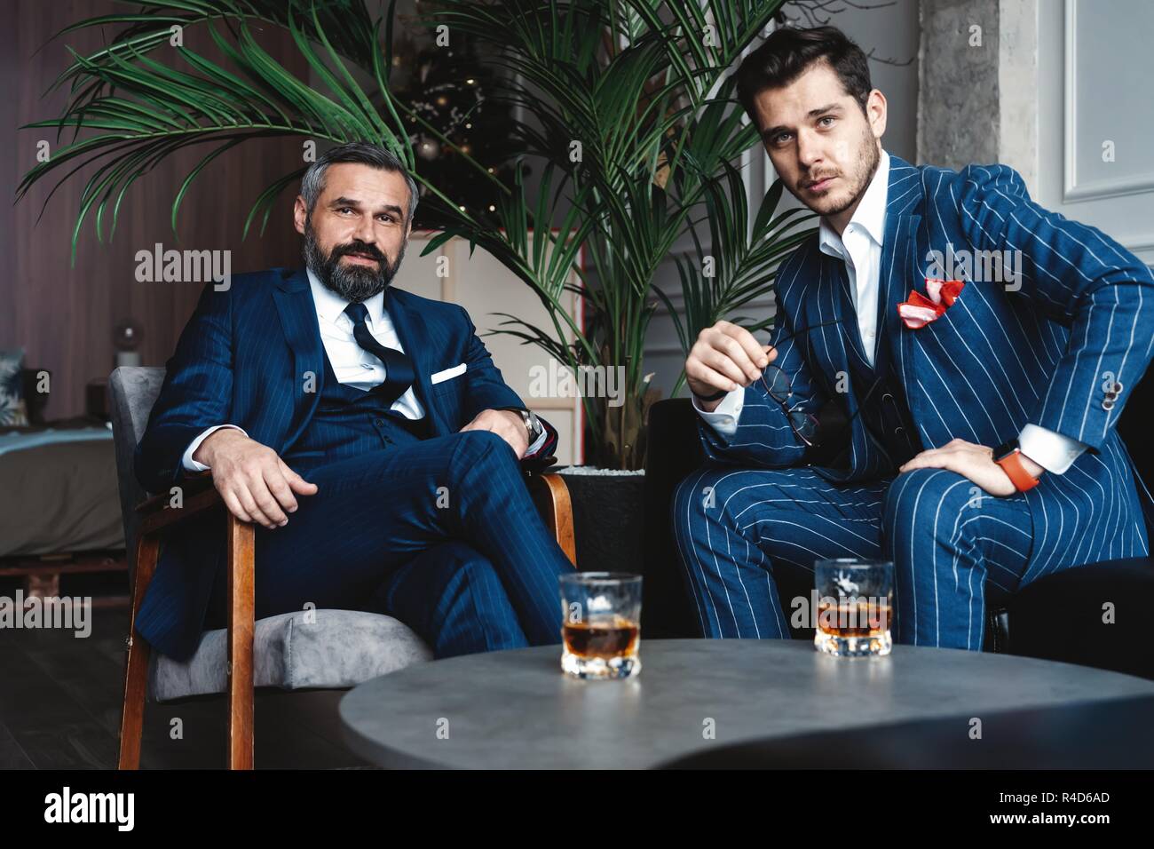 Los hombres con un gran estilo. Dos jóvenes hombres guapos en traje mirando  a la cámara mientras descansa en el interior Fotografía de stock - Alamy