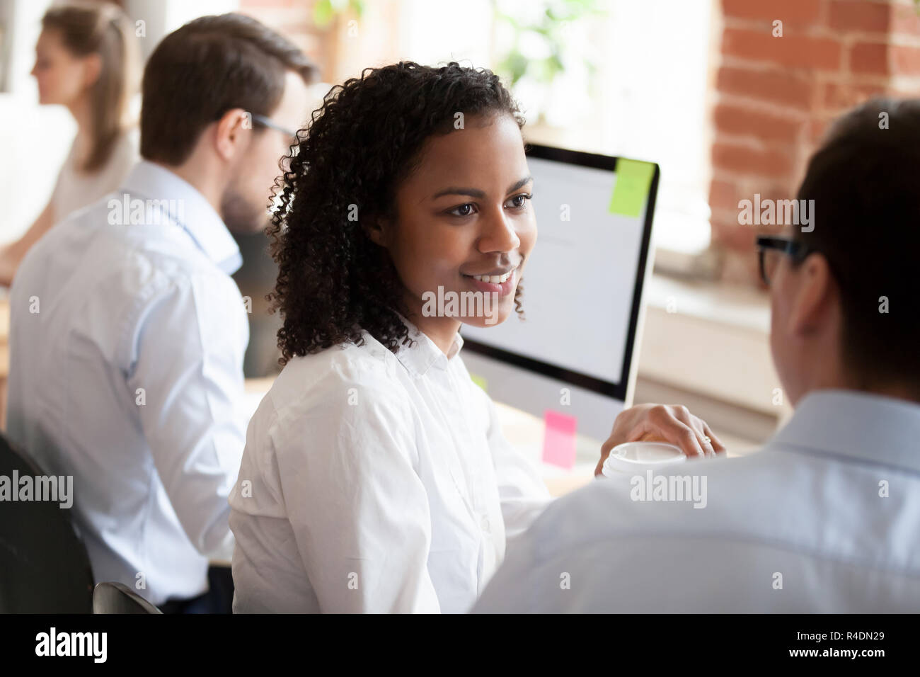 Sonriente joven afroamericana hablando con su colega Foto de stock