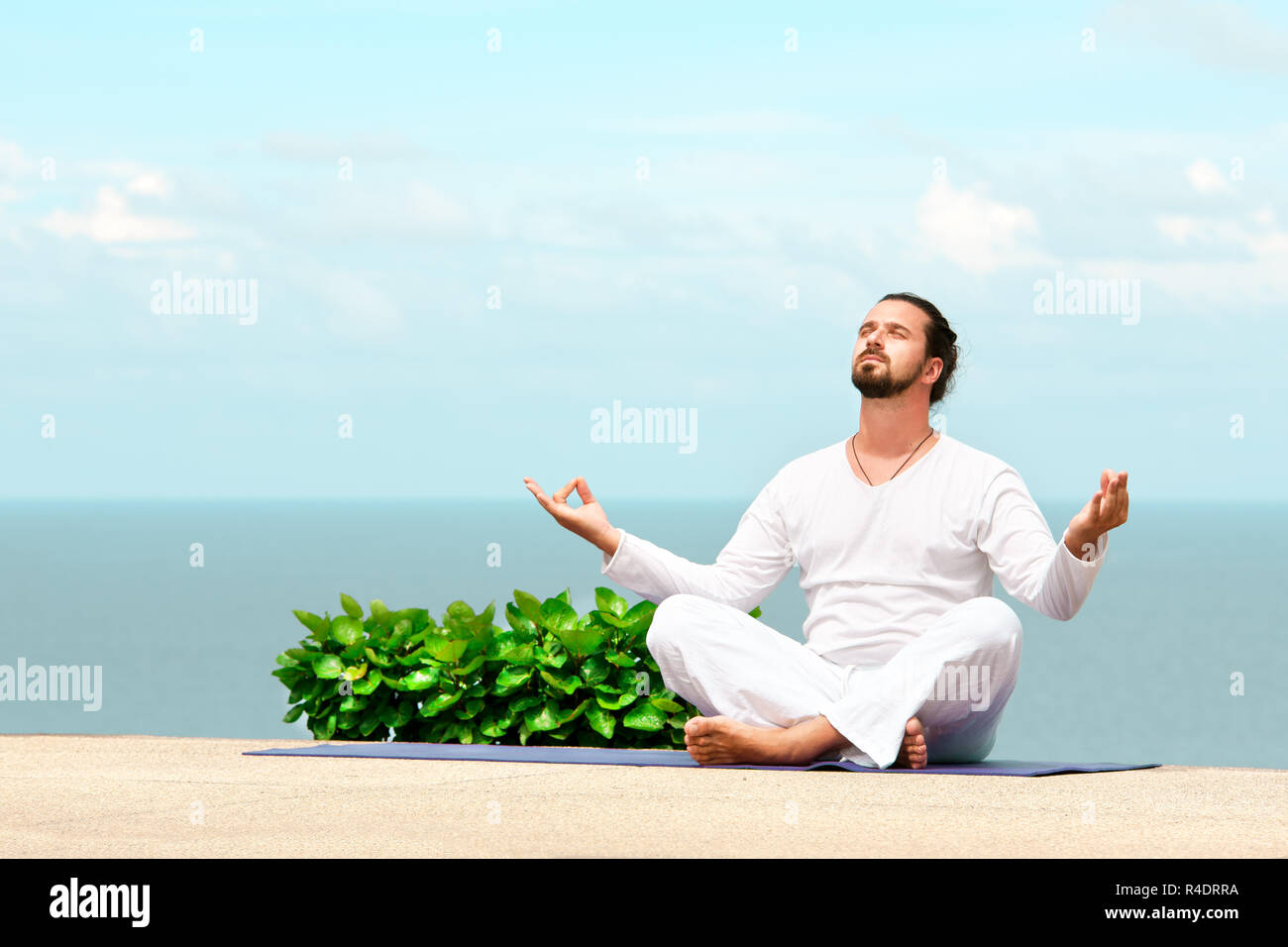 Hombre en ropa blanca meditación yoga en la orilla del mar Fotografía de  stock - Alamy