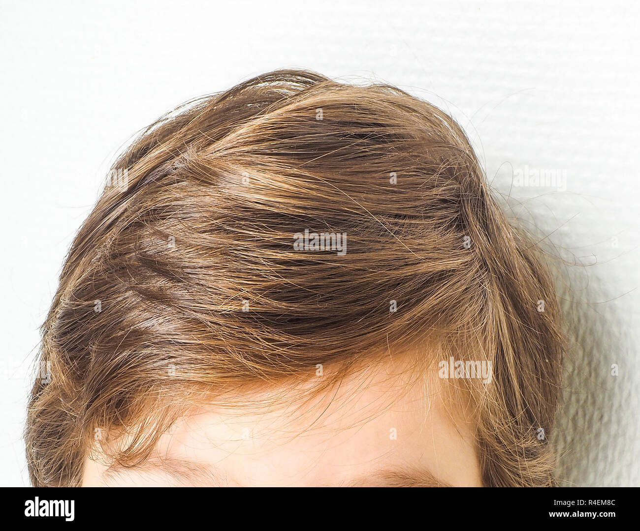 Primer plano de un peinado de neet en un joven, hacia una pared blanca Foto de stock