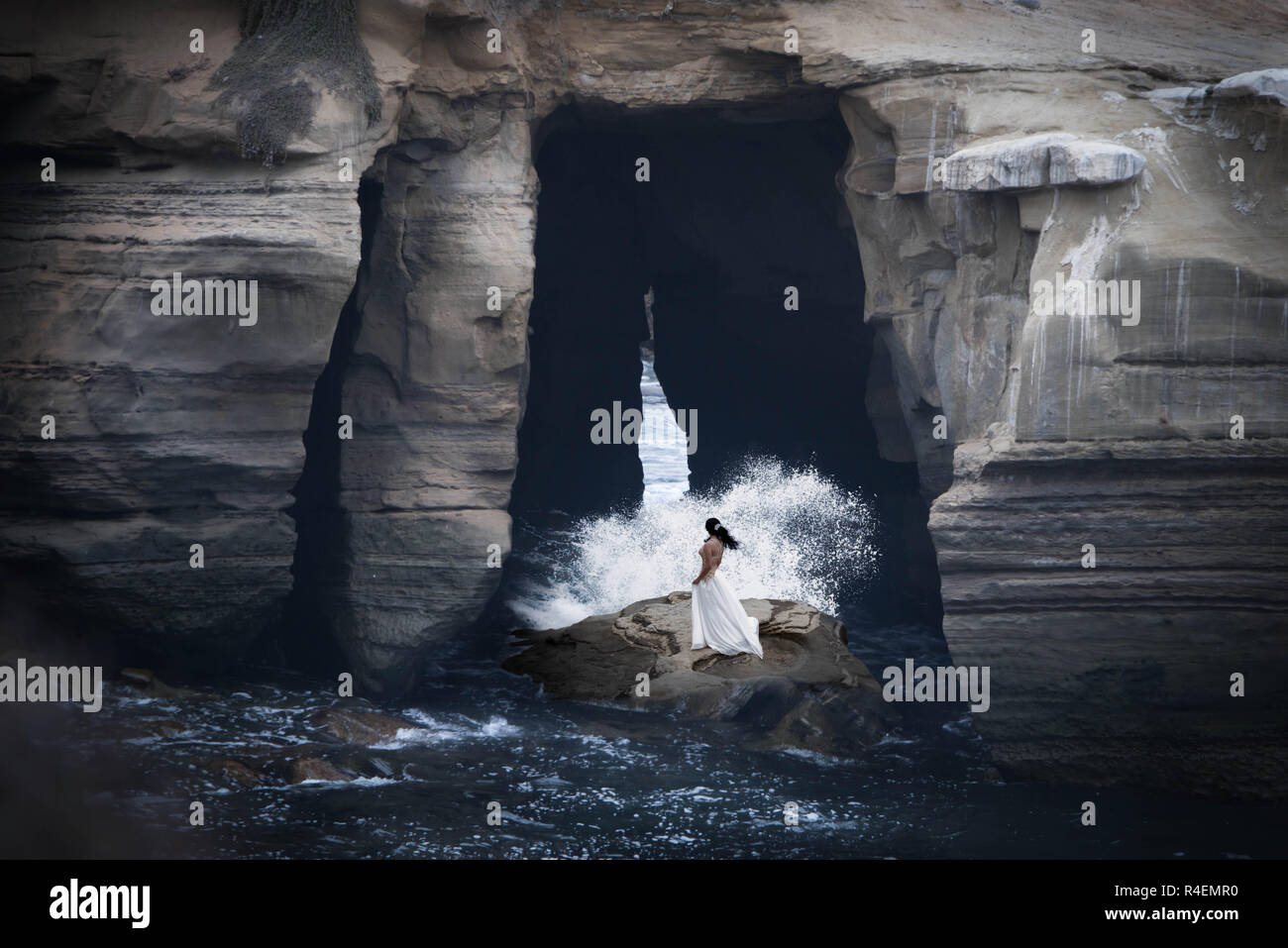 Mujer de pie sobre las rocas en el océano, California, Estados Unidos Foto de stock