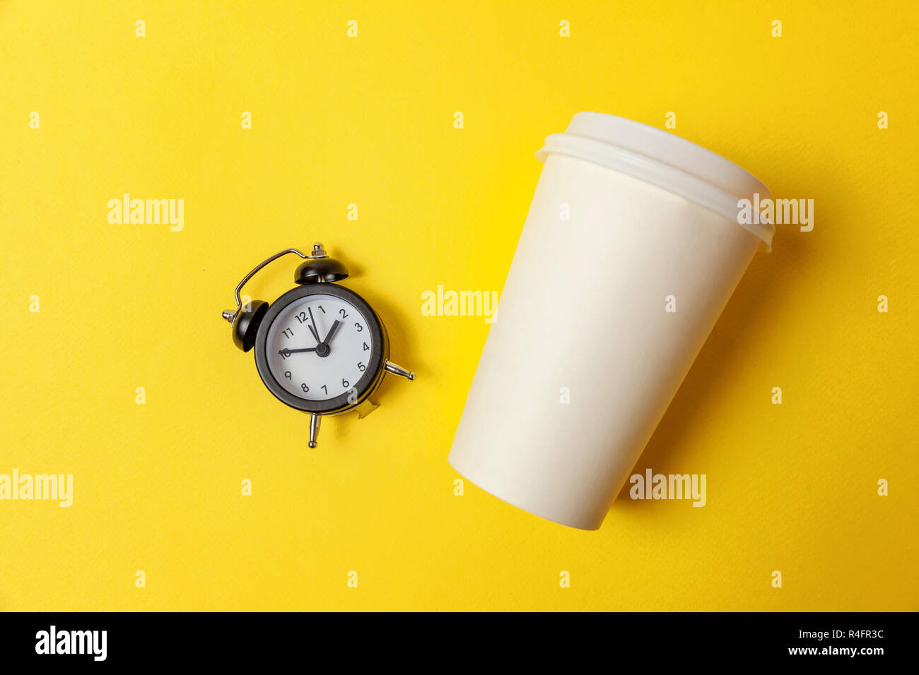 Simplemente sentar diseño plano de la taza de café de papel y despertador  sobre fondo amarillo colorido de moda. Bebida para llevar bebidas y  desayunos. Good morning wake Fotografía de stock -