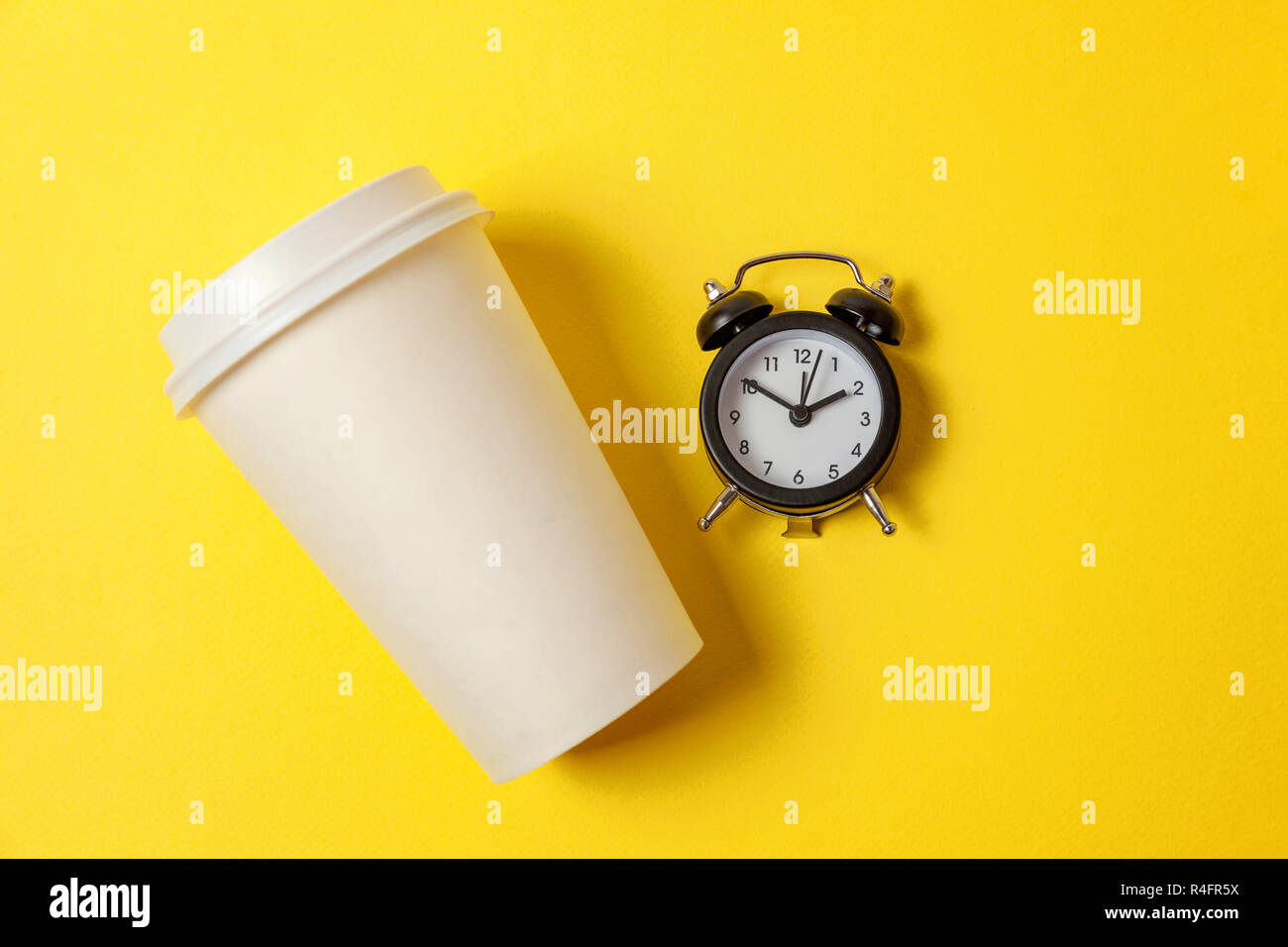 Simplemente sentar diseño plano de la taza de café de papel y despertador  sobre fondo amarillo colorido de moda. Bebida para llevar bebidas y  desayunos. Good morning wake Fotografía de stock -