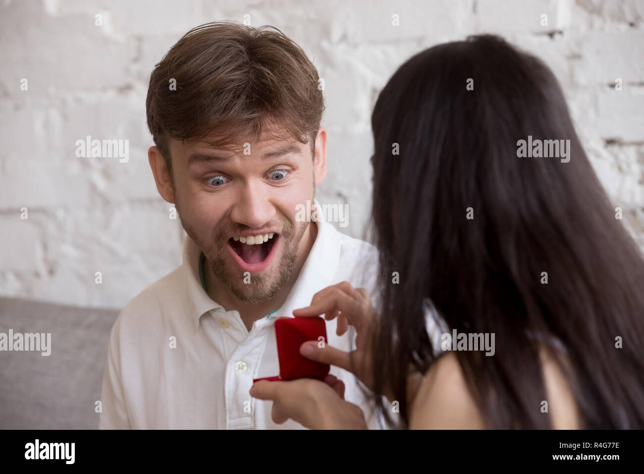 Mujer haciendo propuesta para emocionado sorprendido hombre feliz Foto de stock