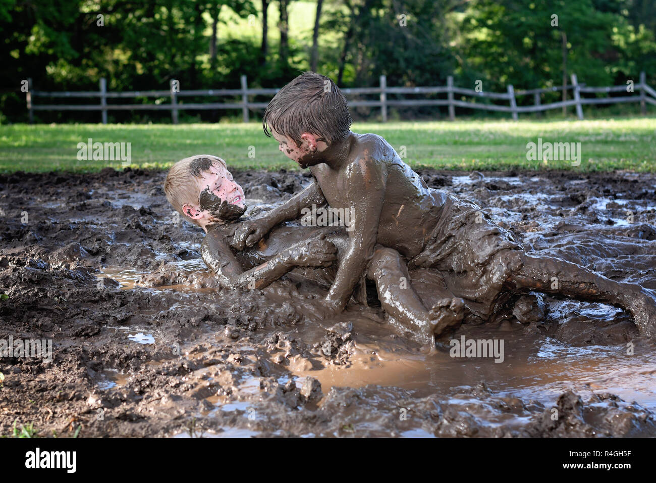 Dos chicos de enlodar y combatiendo en una lucha de barro en el país Foto de stock