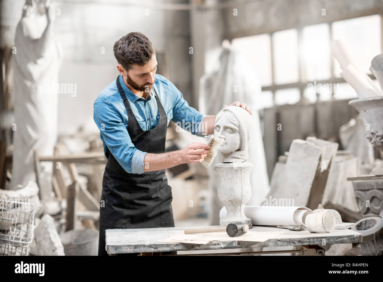Guapo escultor escultura de cepillado de la cabeza de mujer en el lugar de trabajo en el antiguo estudio atmosférico Foto de stock
