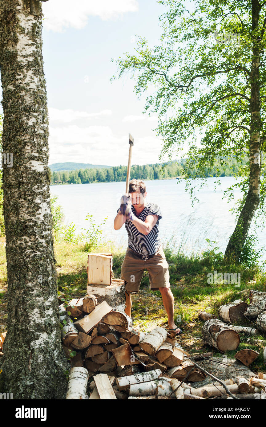 A mediados adulto hombre Cortando troncos en Svadsjo, Suecia Foto de stock