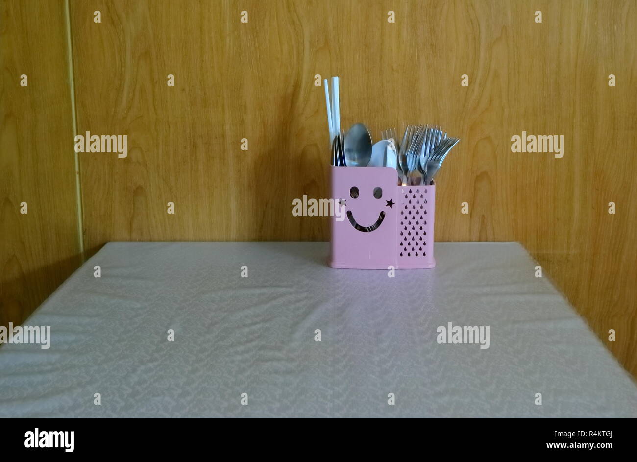 Primer plano de lindo cuadro cubiertos con cara sonriente en la mesa de comedor cubierto con mantel, pensamiento positivo concepto Foto de stock