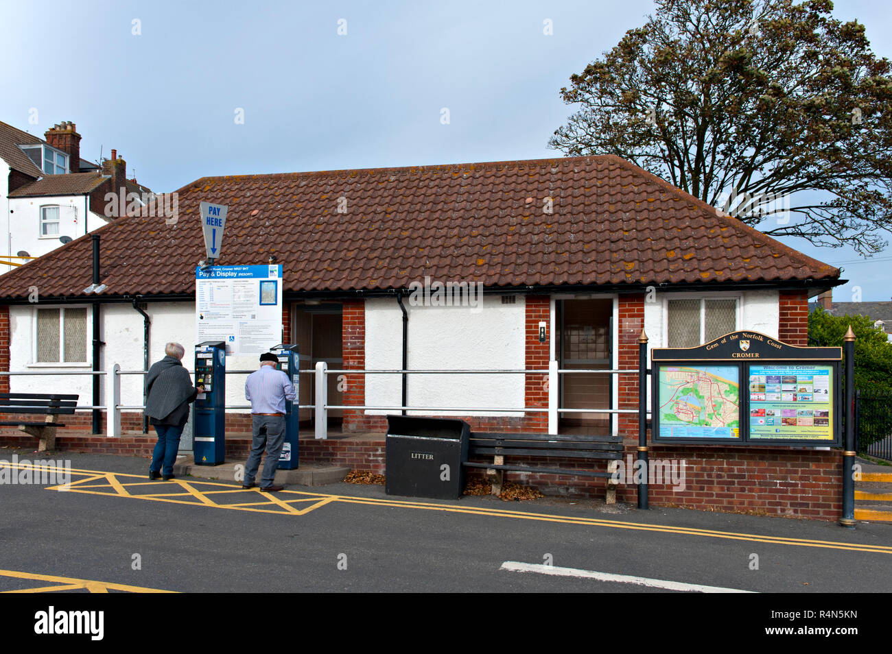 Dos personas obtienen billetes de aparcamiento en un par de coches públicos en Cromer, Norfolk, Reino Unido Foto de stock