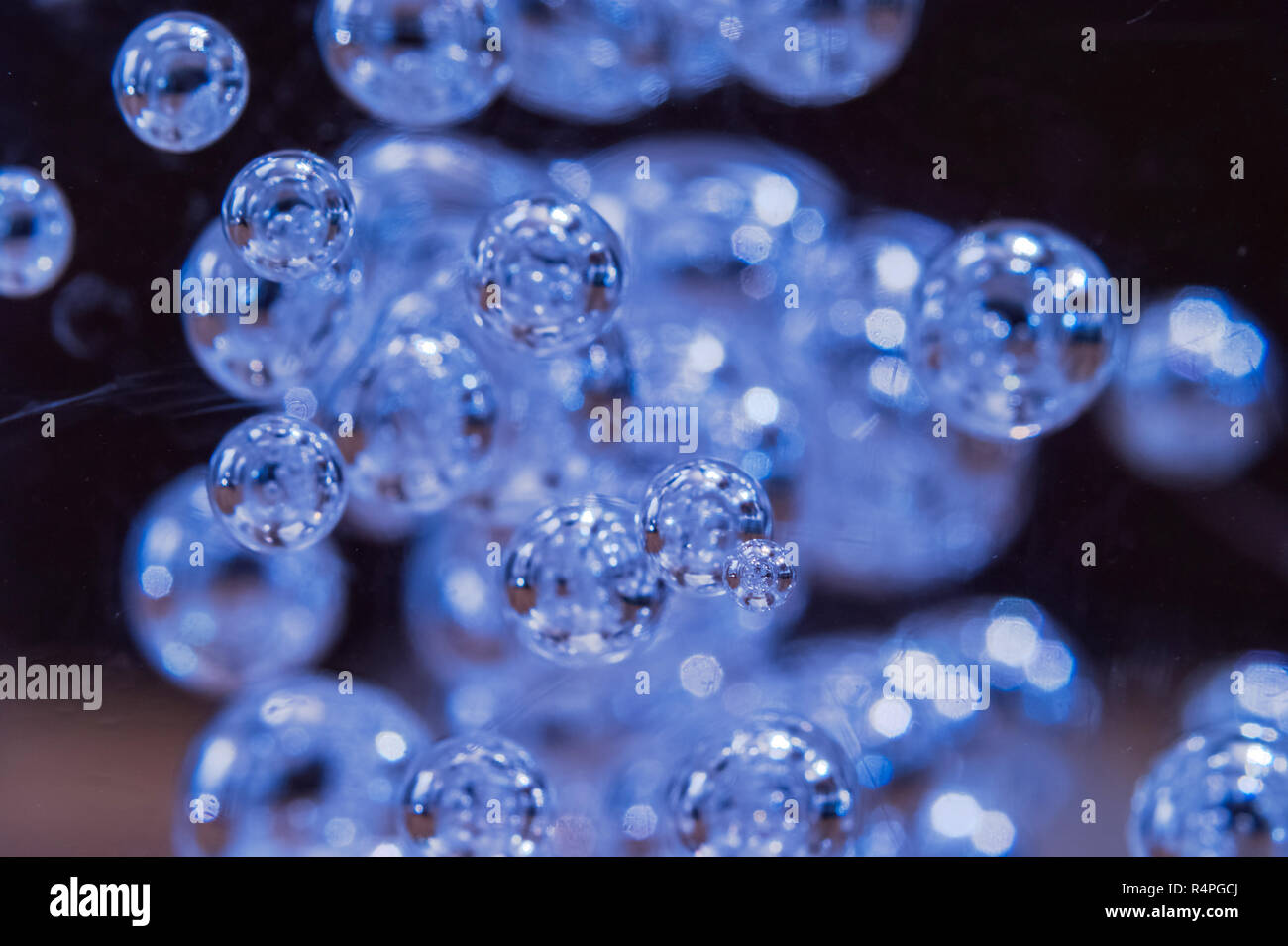 Iluminado en azul burbujas flotando en el líquido claro visto a través del cristal rayado o claraboya. Resumen Antecedentes La textura. Los viajes espaciales, ecología, Envir Foto de stock