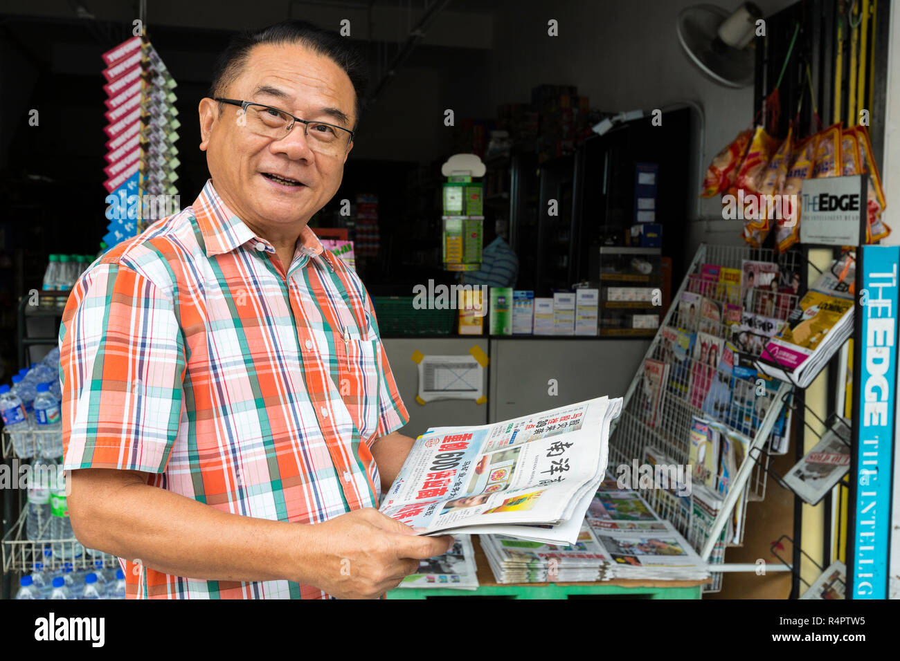 Hombre de mediana edad leyendo el periódico en idioma chino en Ipoh, Malasia. Foto de stock