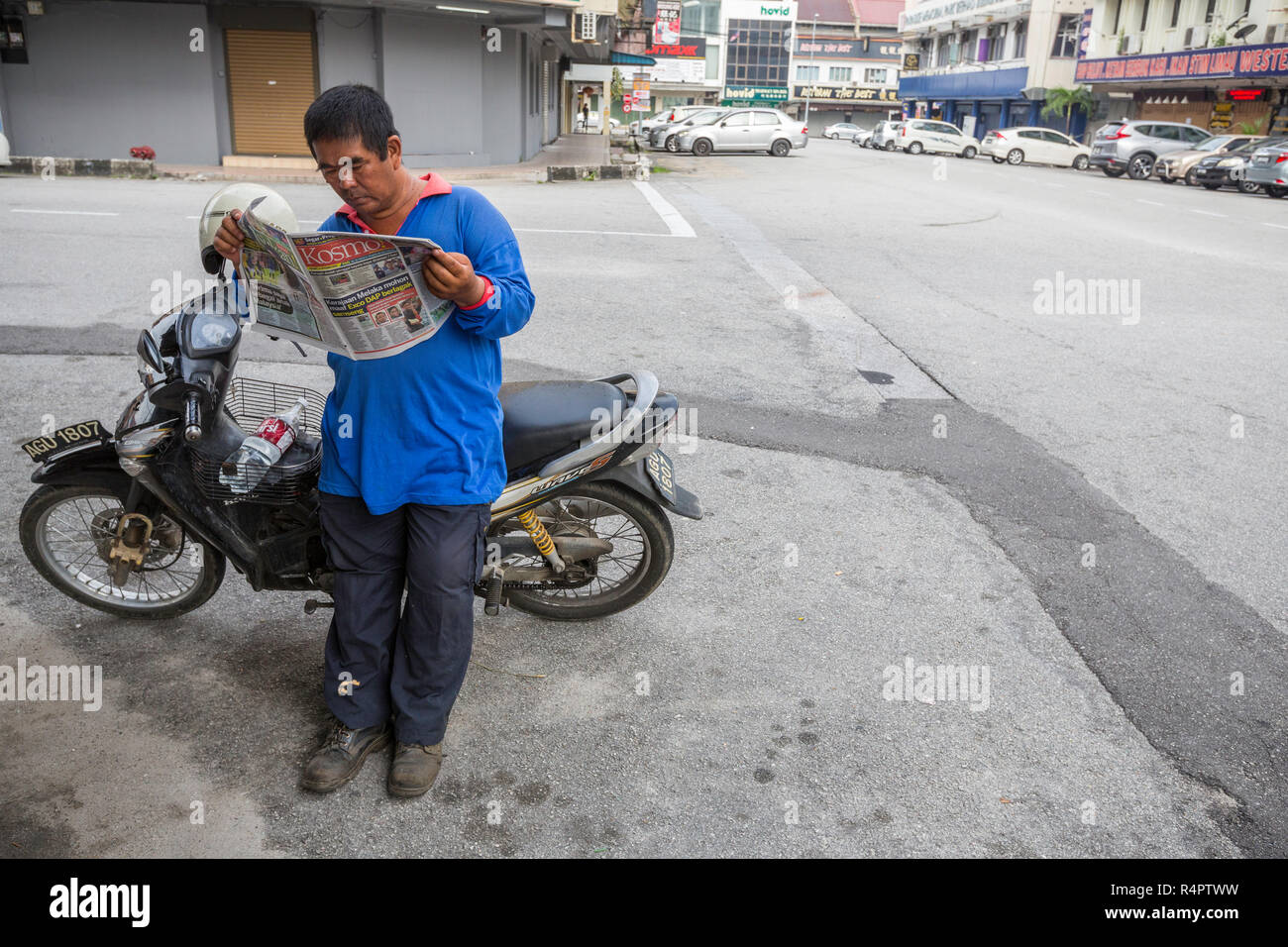 Hombre de mediana edad leyendo el periódico de Malasia en Ipoh, Malasia. Foto de stock