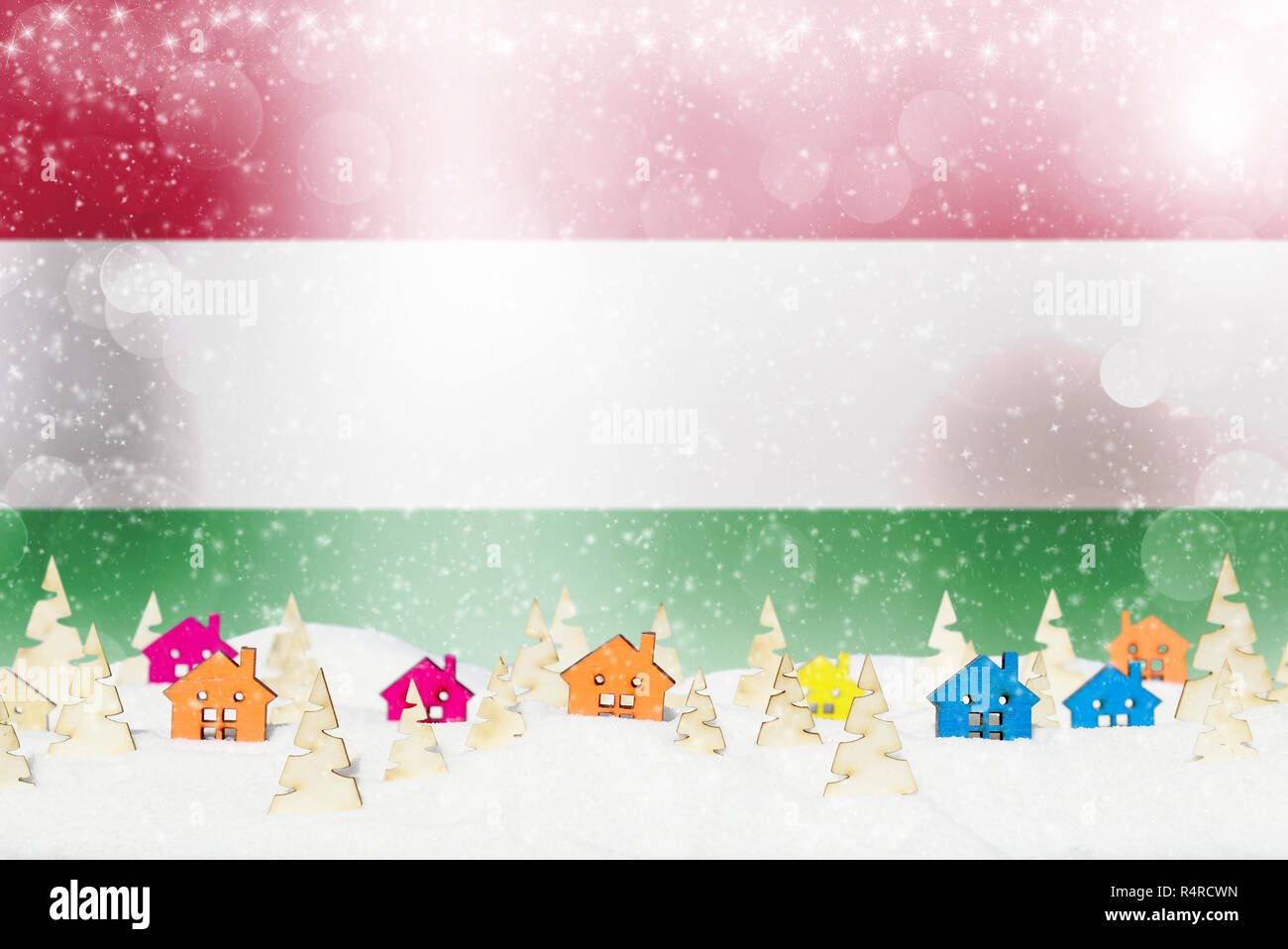 Fondo de navidad con bandera húngara, pequeñas casas de madera, árboles de Navidad y nieve. Foto de stock