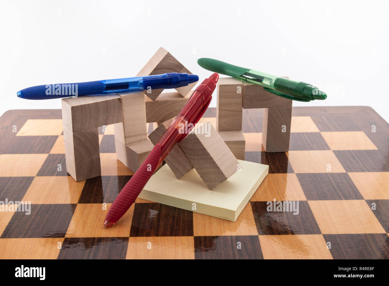 Un tablero de ajedrez y lápices de colores, colocado sobre un fondo blanco, Foto de stock