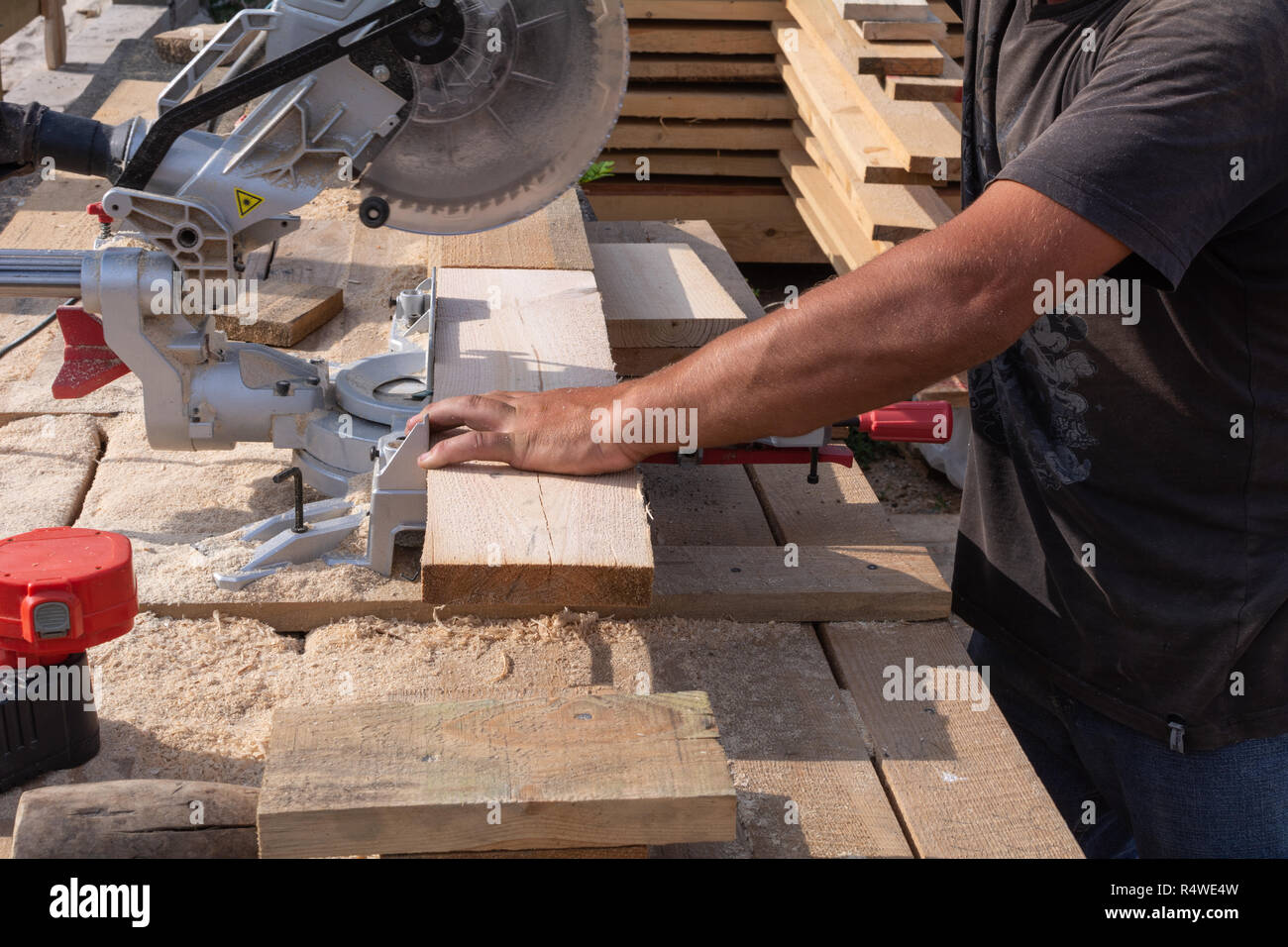 Hombre serrando un tablón de madera con una sierra circular Foto de stock