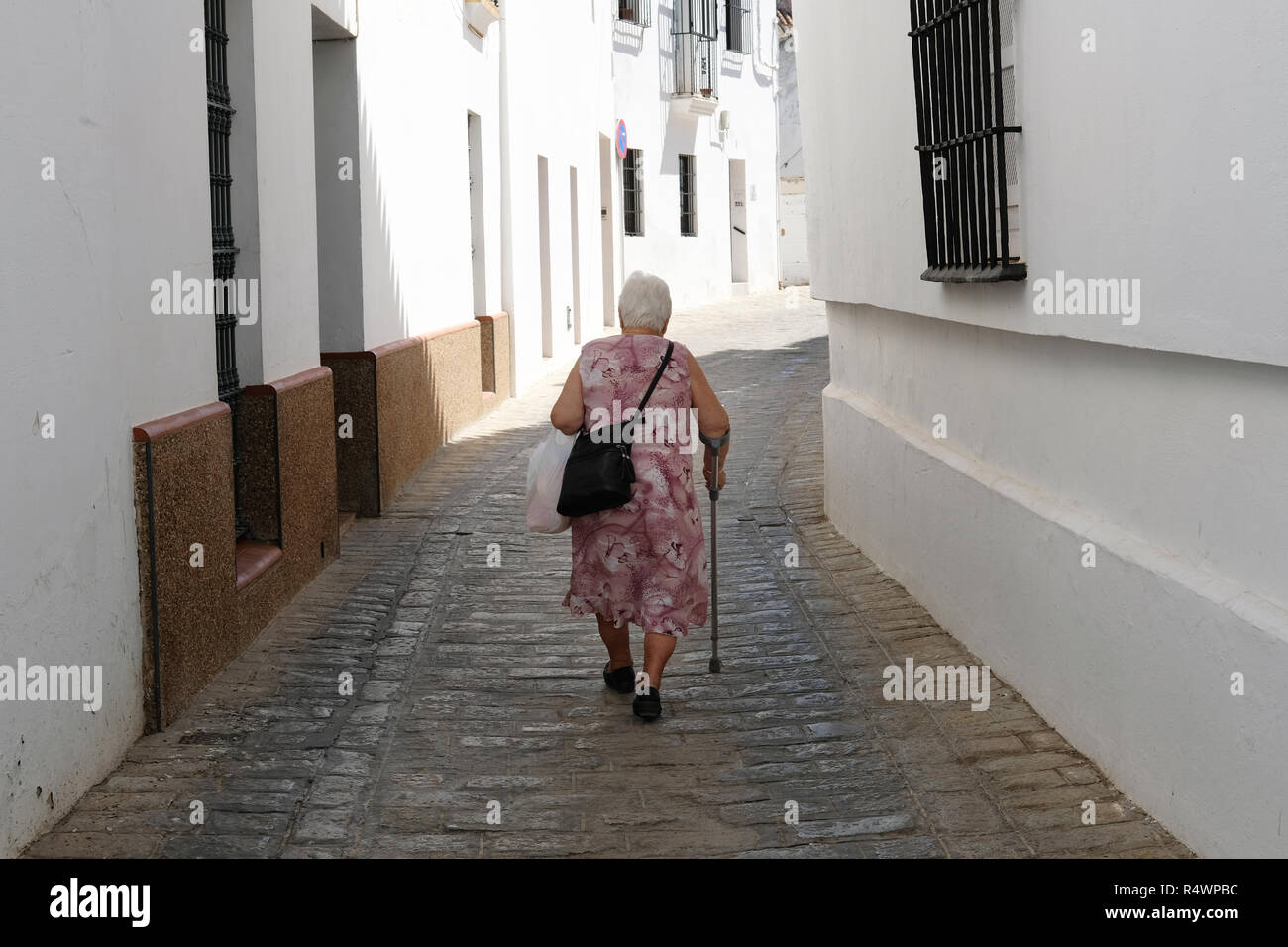 Una vieja mujer española caminando en una ciudad pequeña. Foto de stock