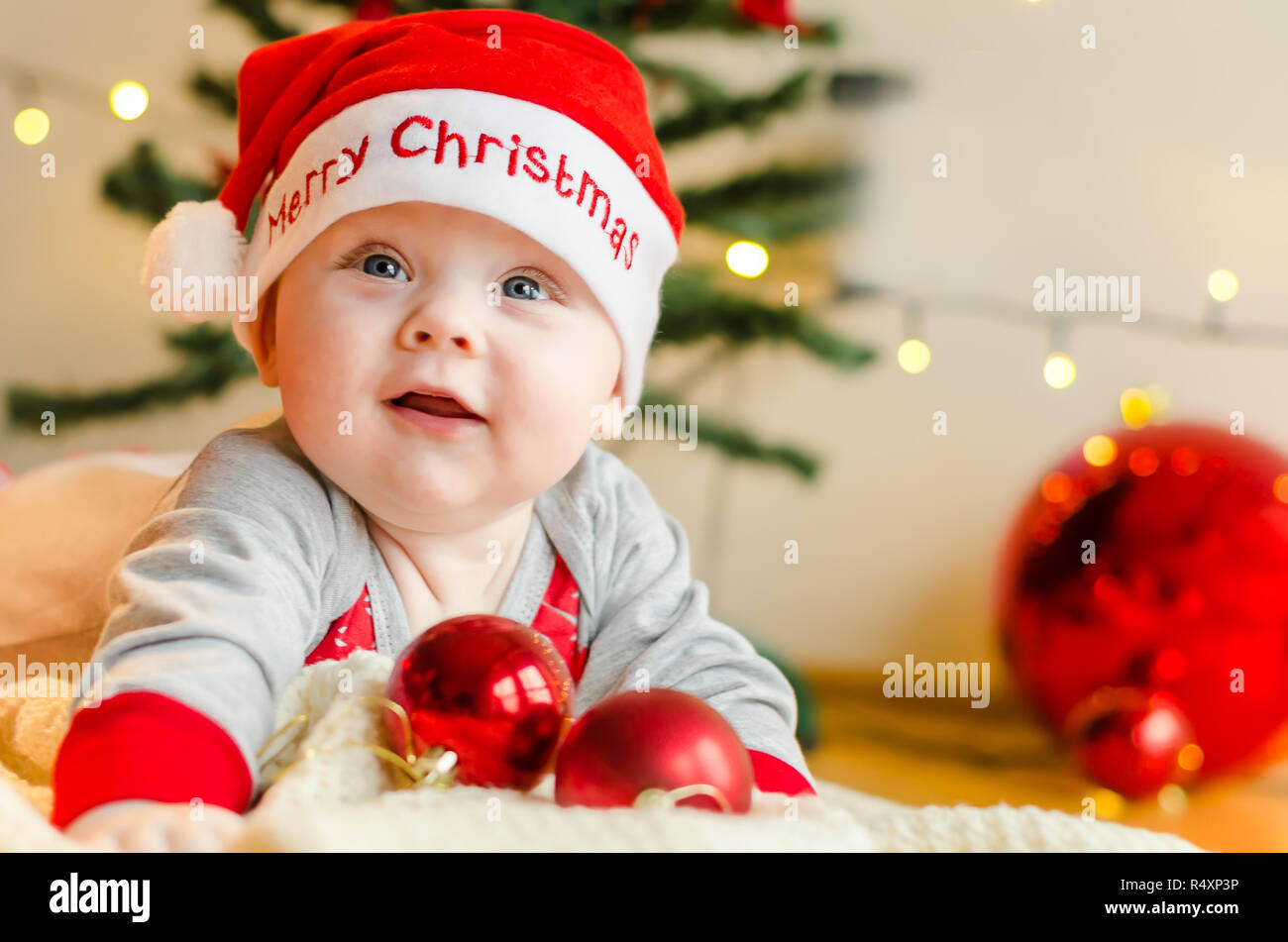 Feliz Navidad Baby Boy alrededor del árbol de Navidad y adornos de Navidad esperando Foto de stock