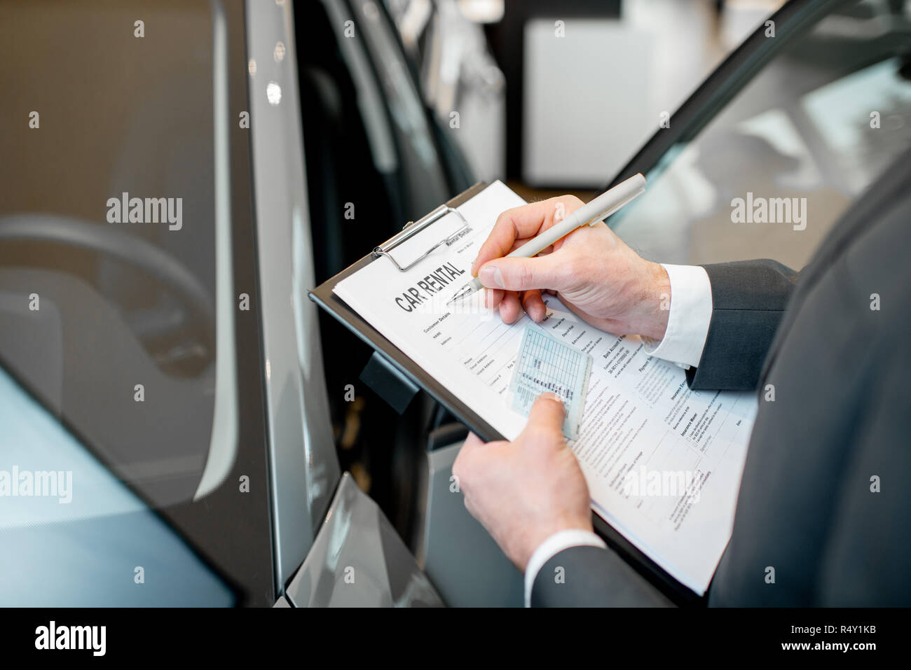 Gerente de servicio del vehículo llenado documentos celebración carpeta con  licencia de conducir en el showroom con el coche en el fondo Fotografía de  stock - Alamy