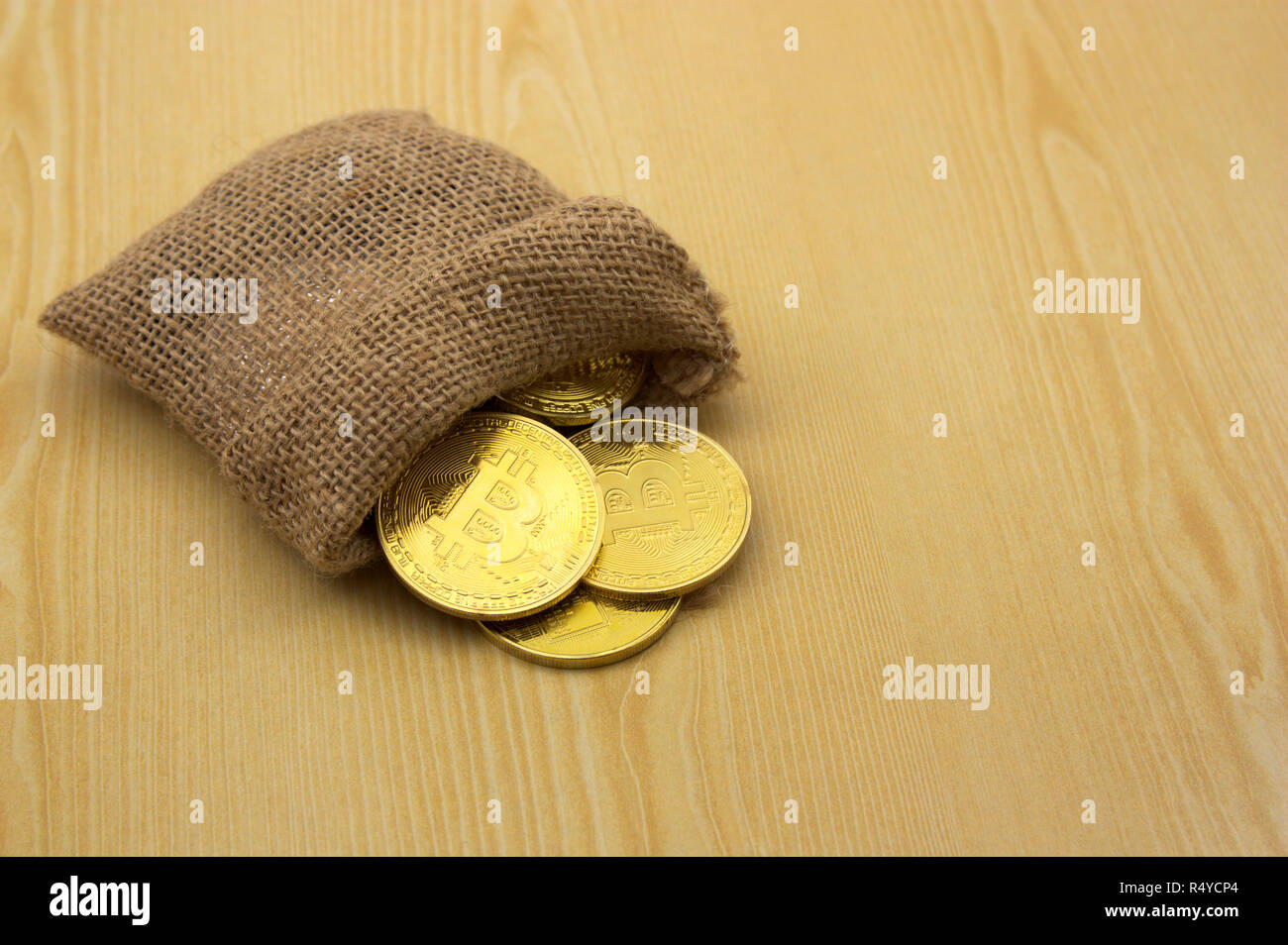 Algunas monedas Bitcoin oro almacenado en un saco marrón sobre una tabla de madera Foto de stock