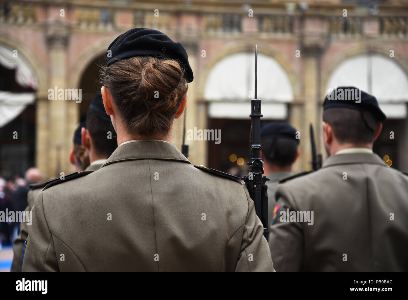 Detalle uniformados con mujeres de pie durante la ceremonia militar en  Bolonia, Italia. En primer plano, una mujer Vistos desde atrás con un fusil  de bayoneta Fotografía de stock - Alamy