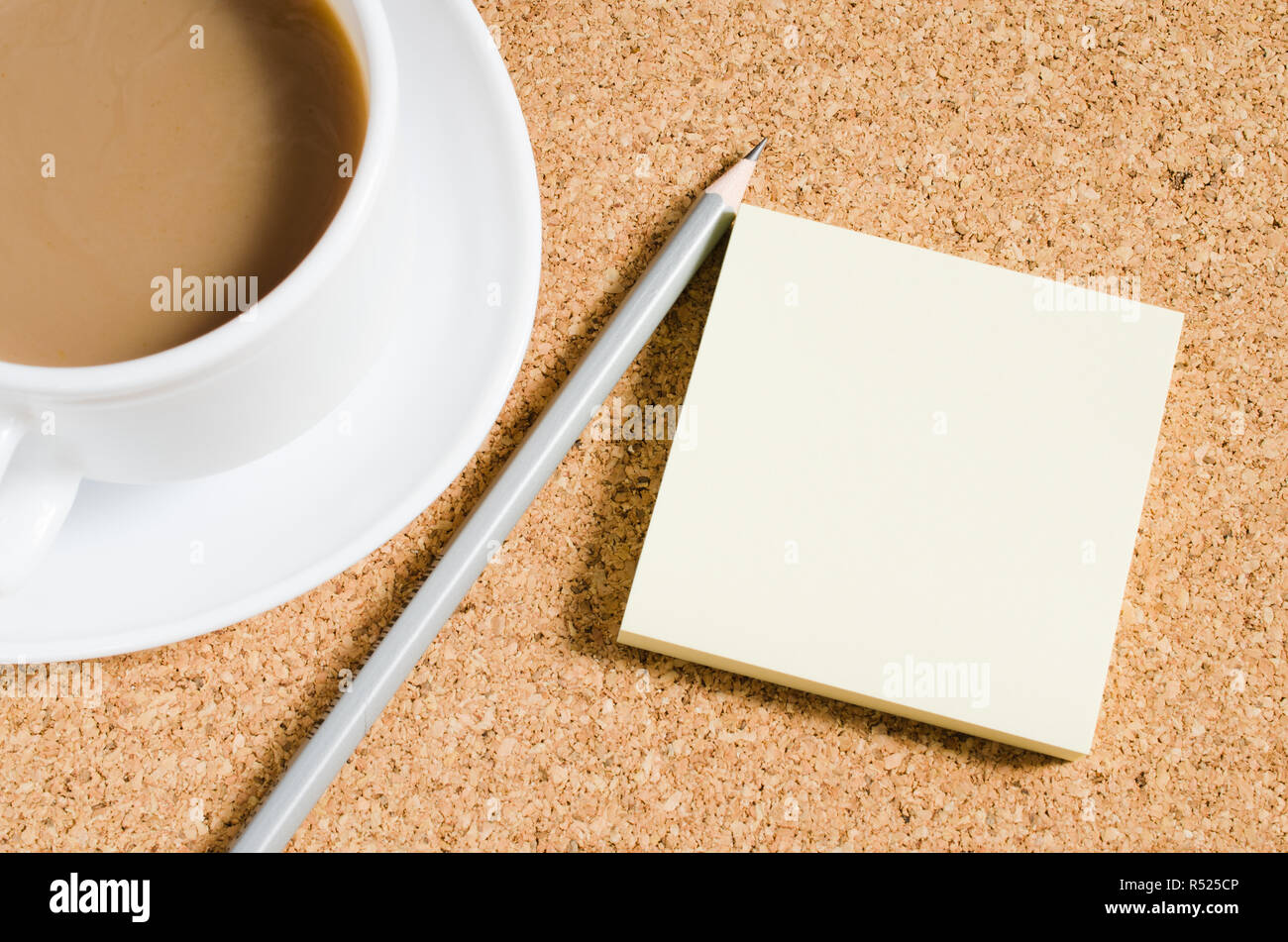 Notas en blanco y la taza de café sobre el tablero de corcho Foto de stock