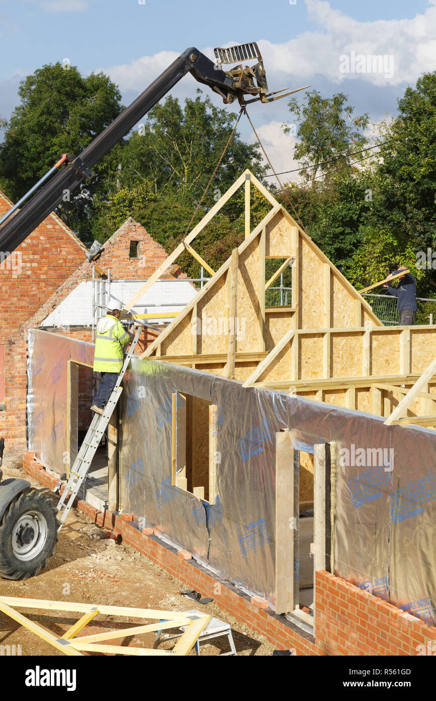 Buckingham, Reino Unido - 13 de octubre de 2016. Un constructor en trabajar en una obra en construcción en el Reino Unido instala vigas de techo a una extensión de la casa de marcos de madera Foto de stock